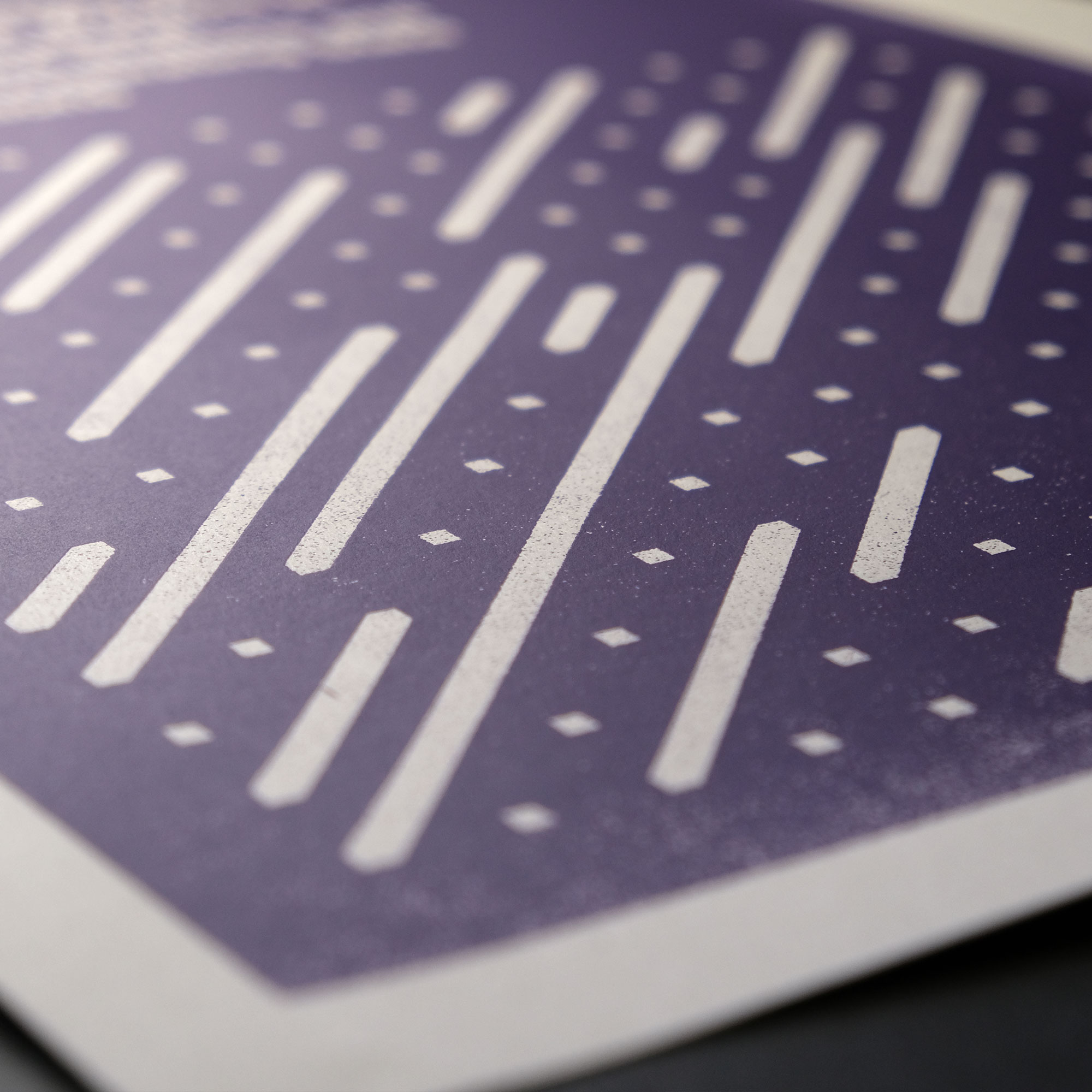 A purple silkscreened print of USDA report 1984-85 Directory of Professional Workers in State Agricultural Experiment Stations and Other Cooperating State Institutions which has geometric shapes in white and purple and the print sits on a wood surface