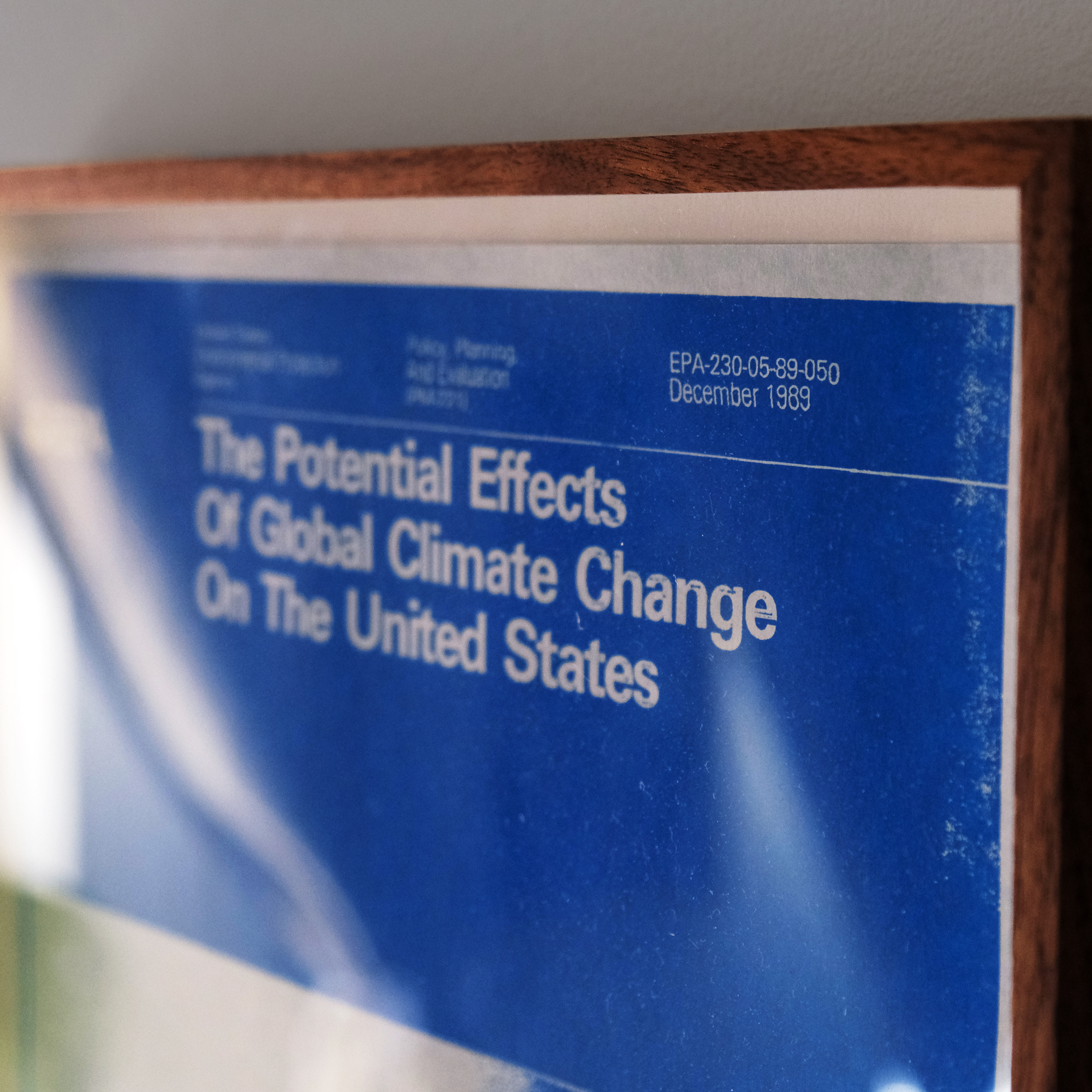 A photo of a framed vintage EPA poster from 1989 titled The Potential Effects of Global Climate Change on the United States, blue on blue paper, with a blue Earth