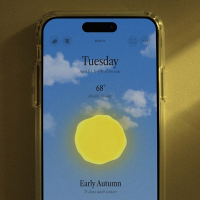 A close up view of the app Ambient Almanac shows a daytime scene with a yellow orb and blue sky and clouds