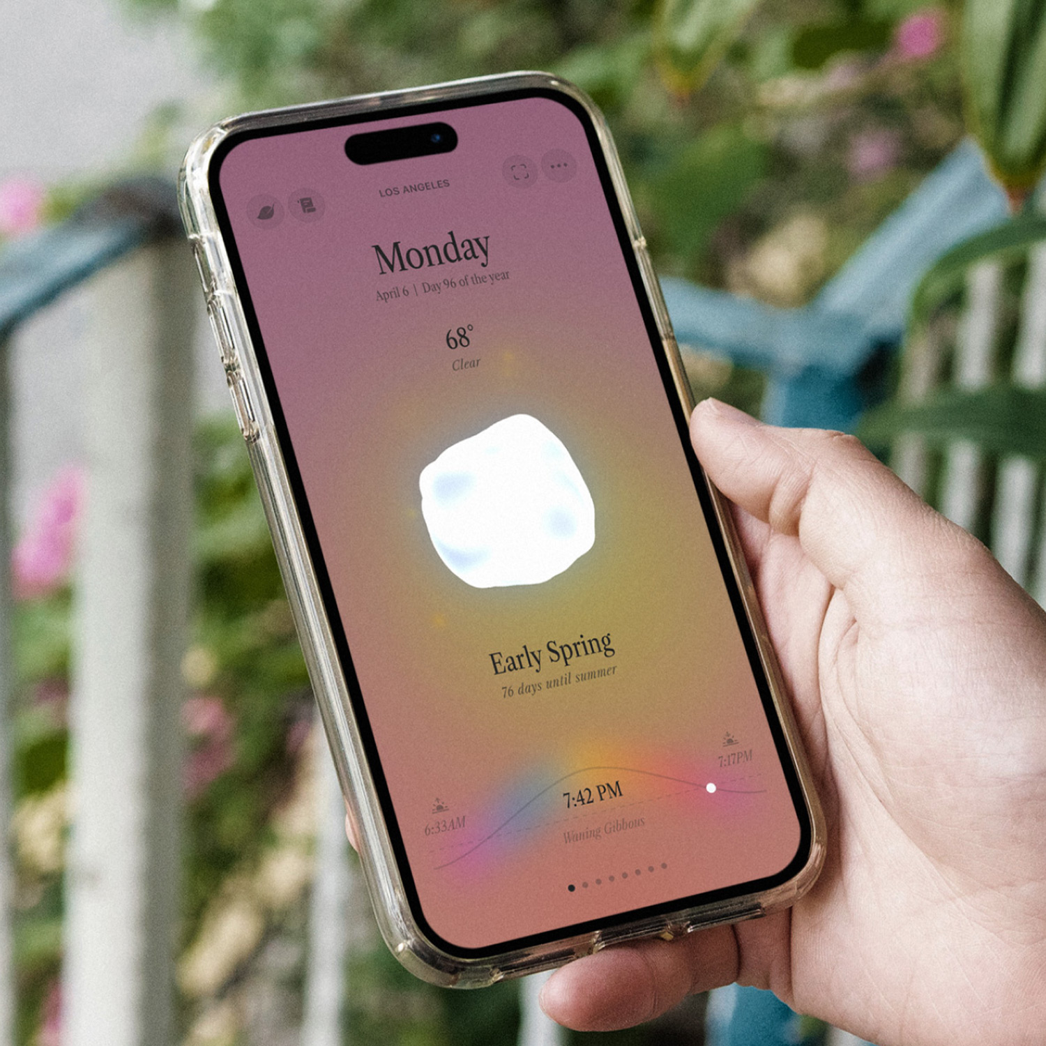 A hand holding a mobile phone with the Ambient Almanac app running