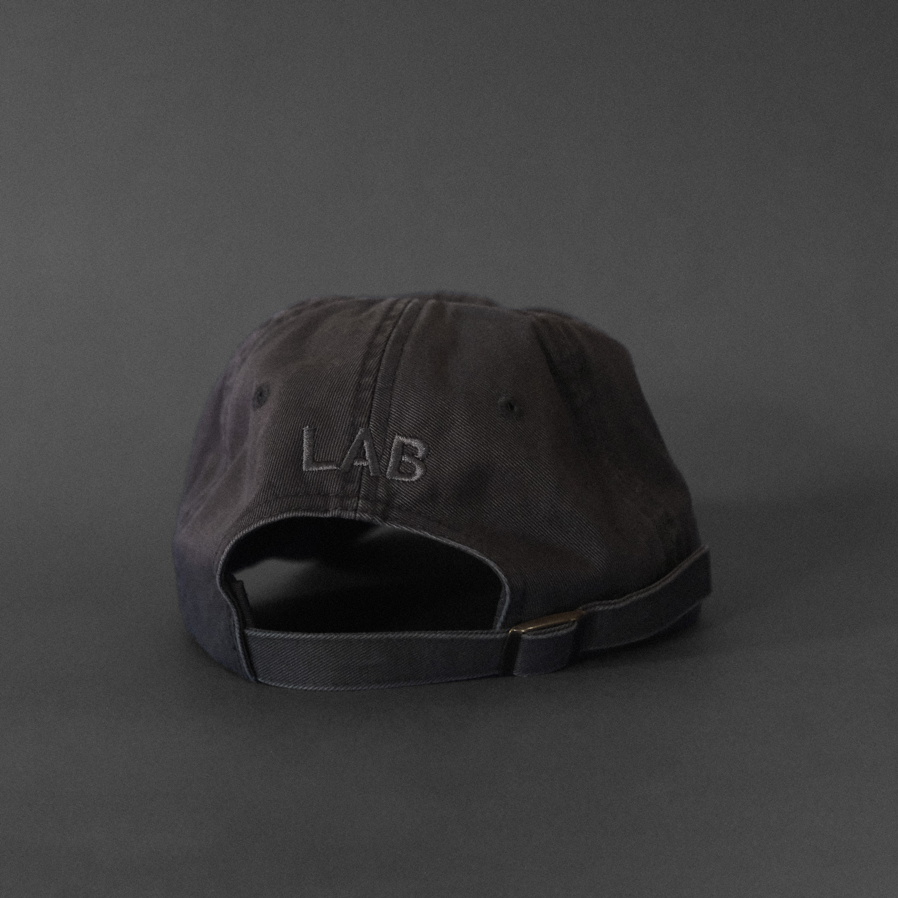 A dark gray cap with dark gray embroidered text that says LAB on a dark gray background
