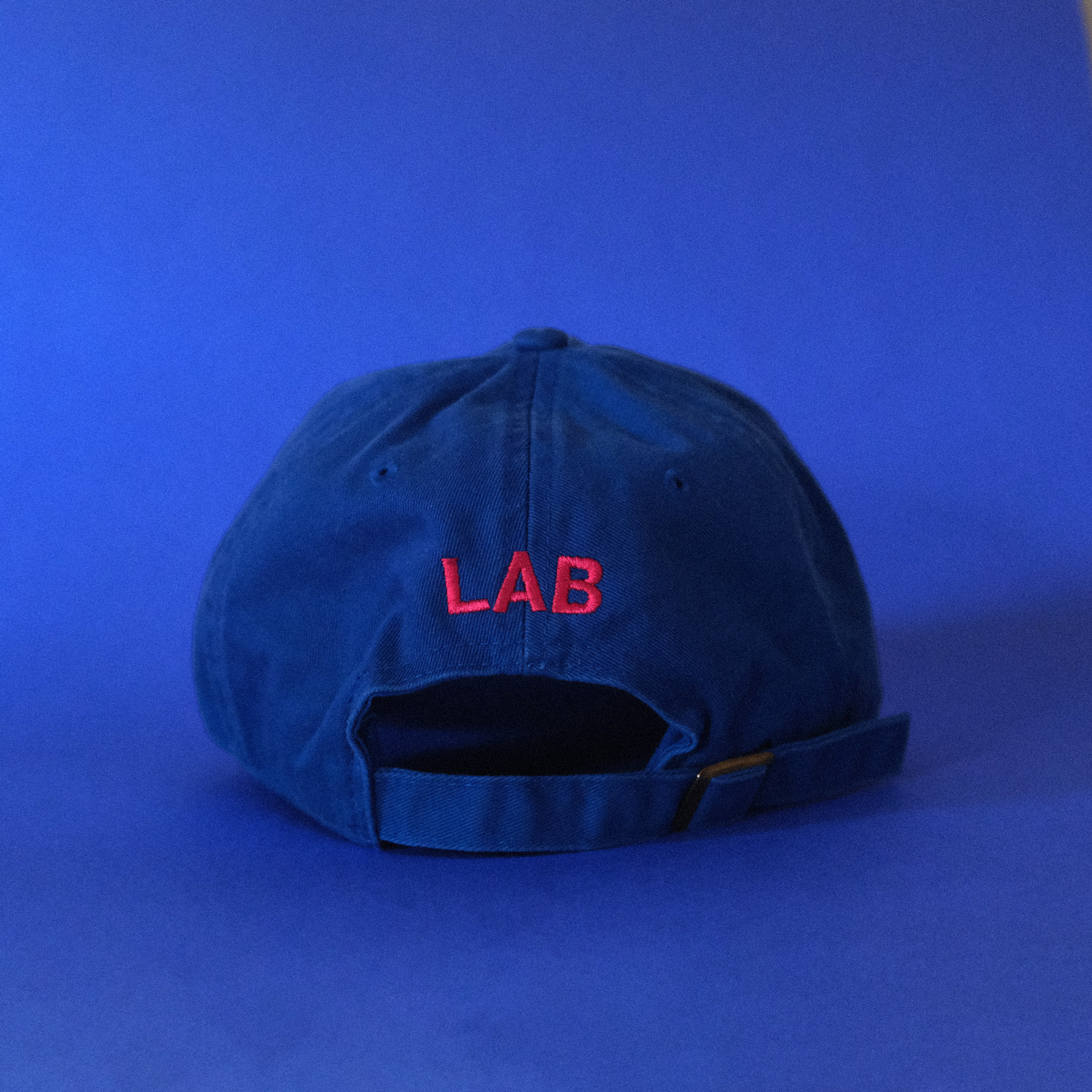 A bright blue cap with red embroidered text that says LAB on a blue background