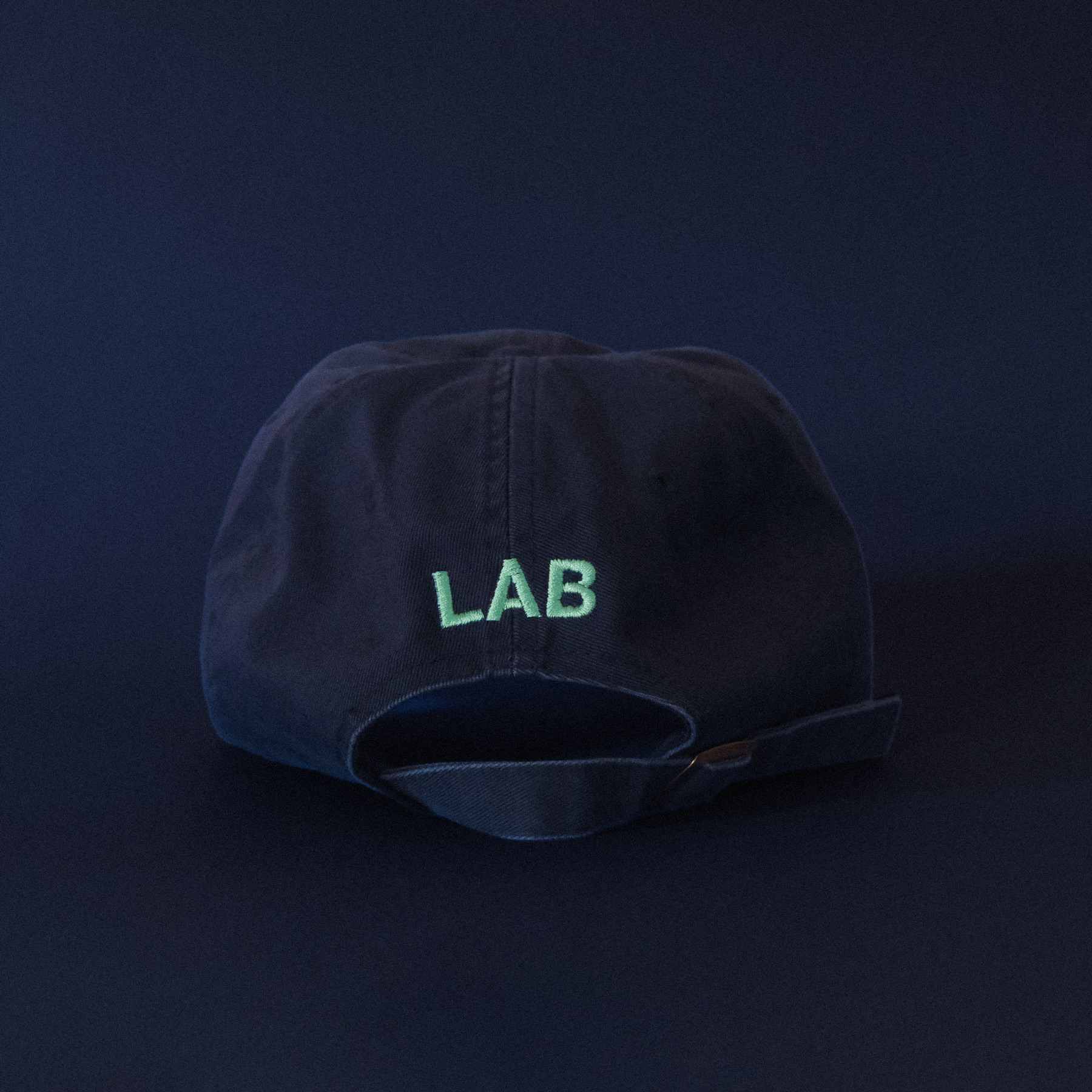 A dark blue cap with mint embroidered text that says LAB on a dark blue background